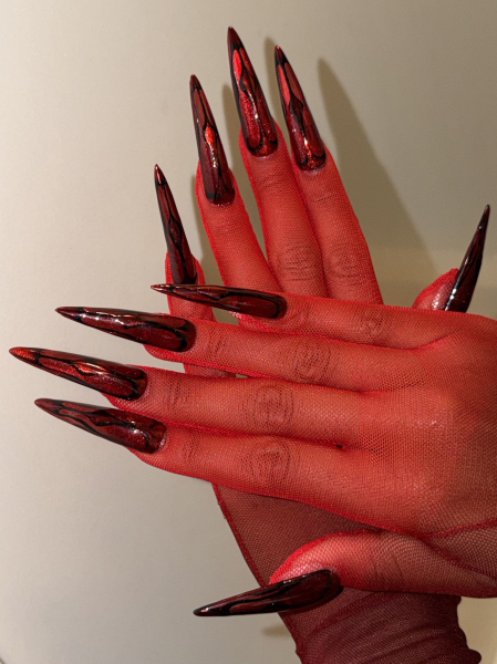A photo of Naomi Osaka's hands and nails for the 2026 Met Gala. She's wearing red mesh gloves and her nails are long...